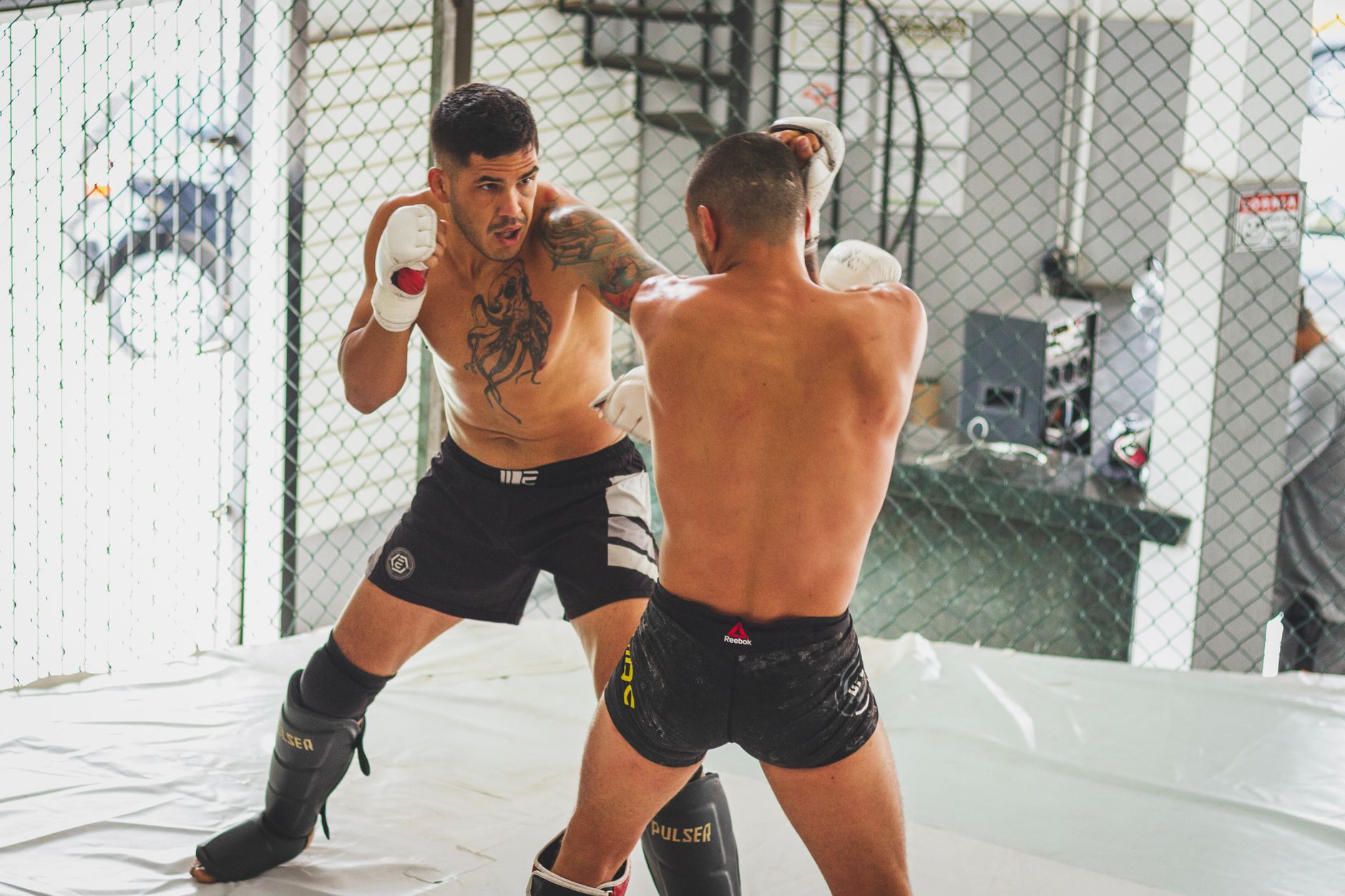 MMA sparring between two athletes in a gym setting, showcasing skill and intensity.