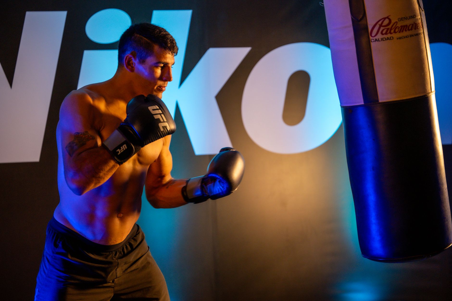 A male boxer exercises with a punching bag in a gym in Mexico City, showcasing fitness and strength.