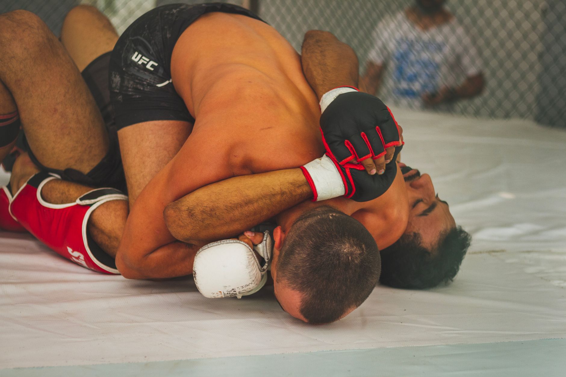 Two MMA fighters grappling on the mat during a match, showcasing intensity and skill.