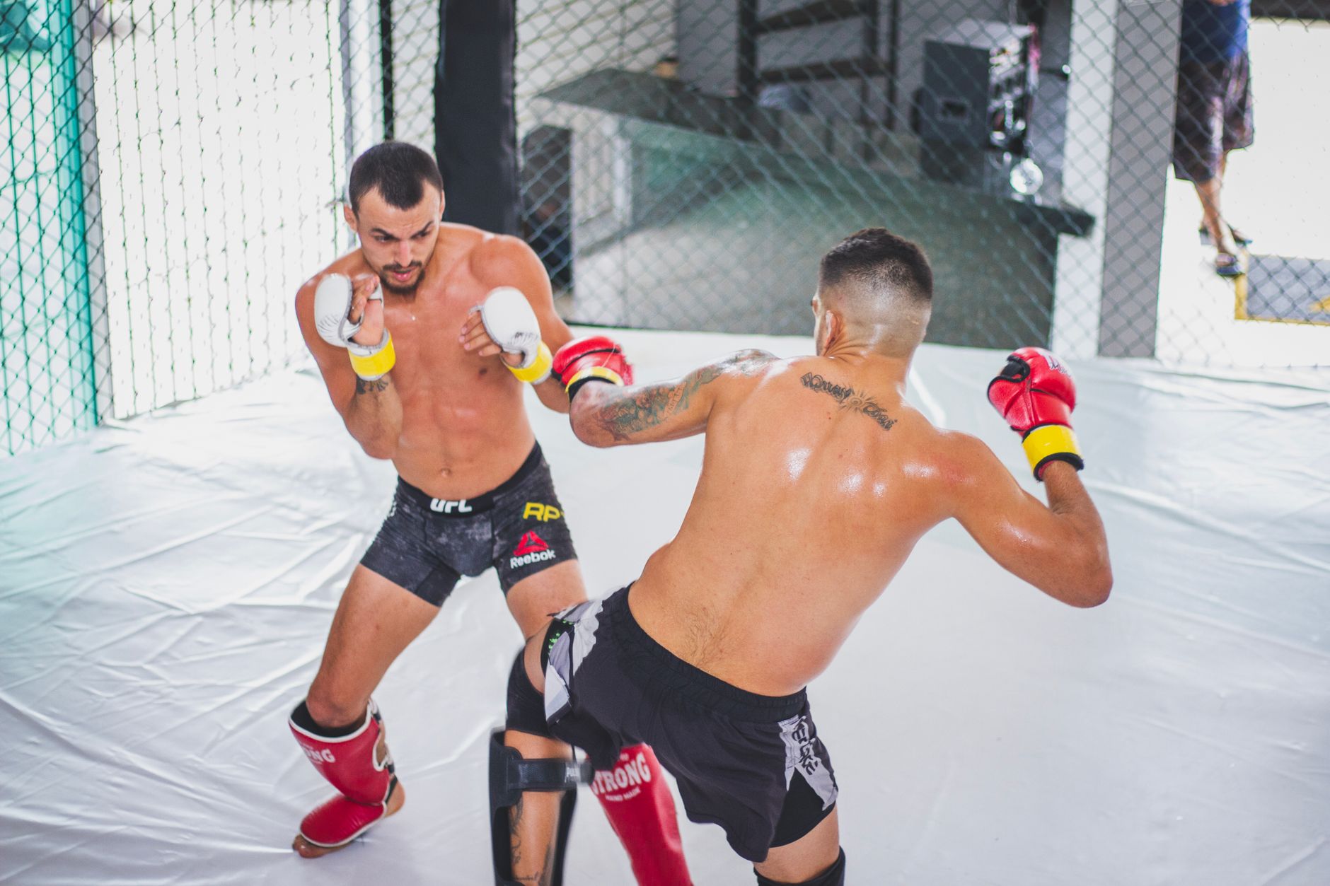 Two men engage in mixed martial arts training inside an octagon, showcasing skill and strength.