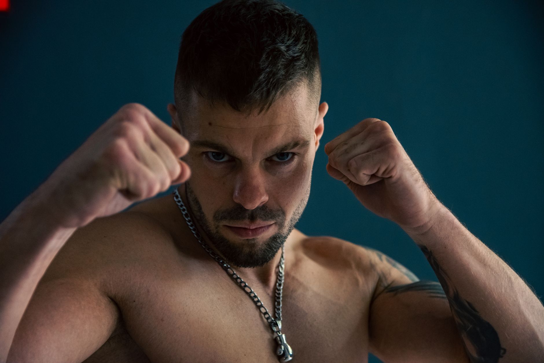 Strong and focused man posing with fists raised, showcasing power and determination in a studio setting.