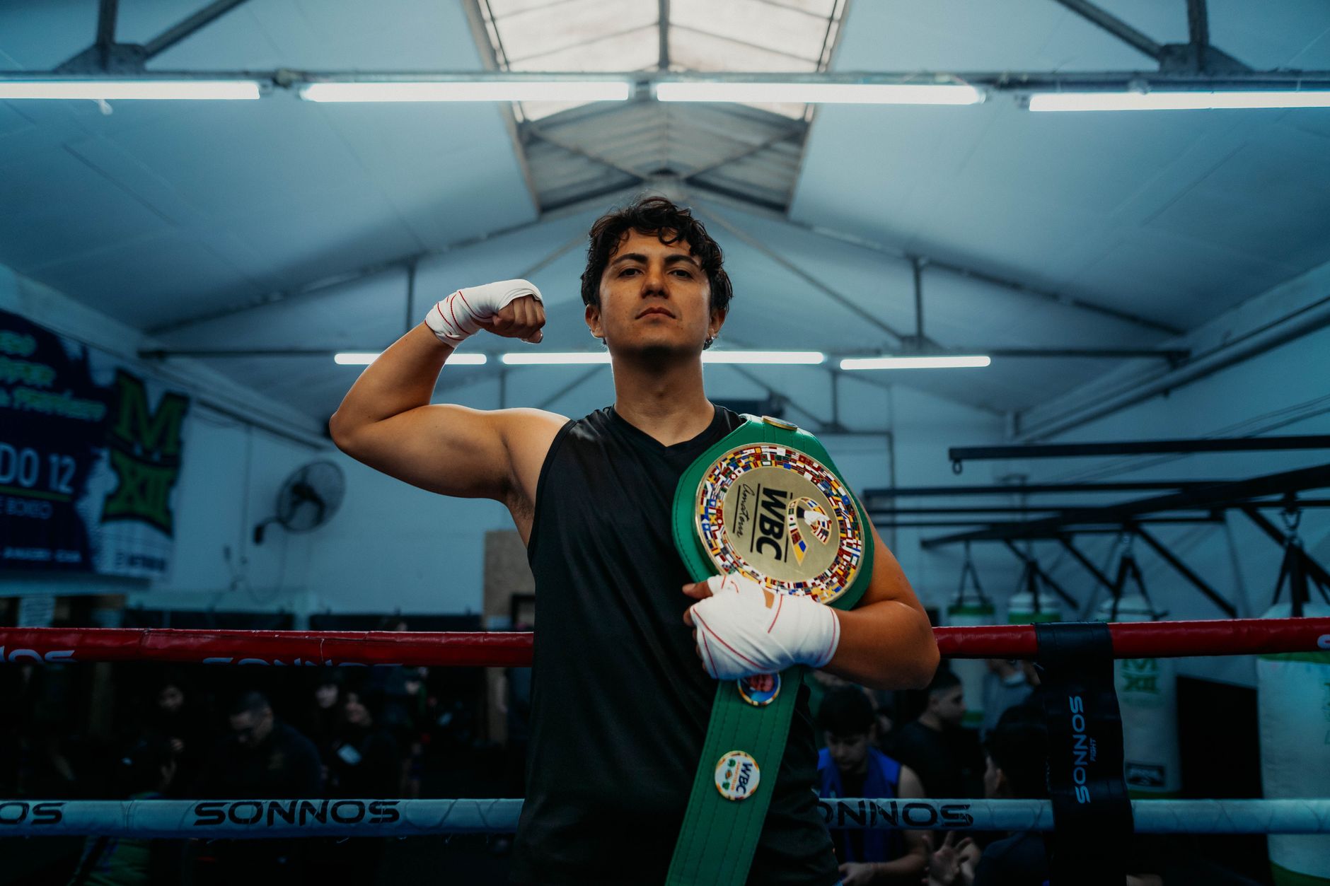 Boxer proudly holding a WBC championship belt in an indoor gym setting, Buenos Aires.