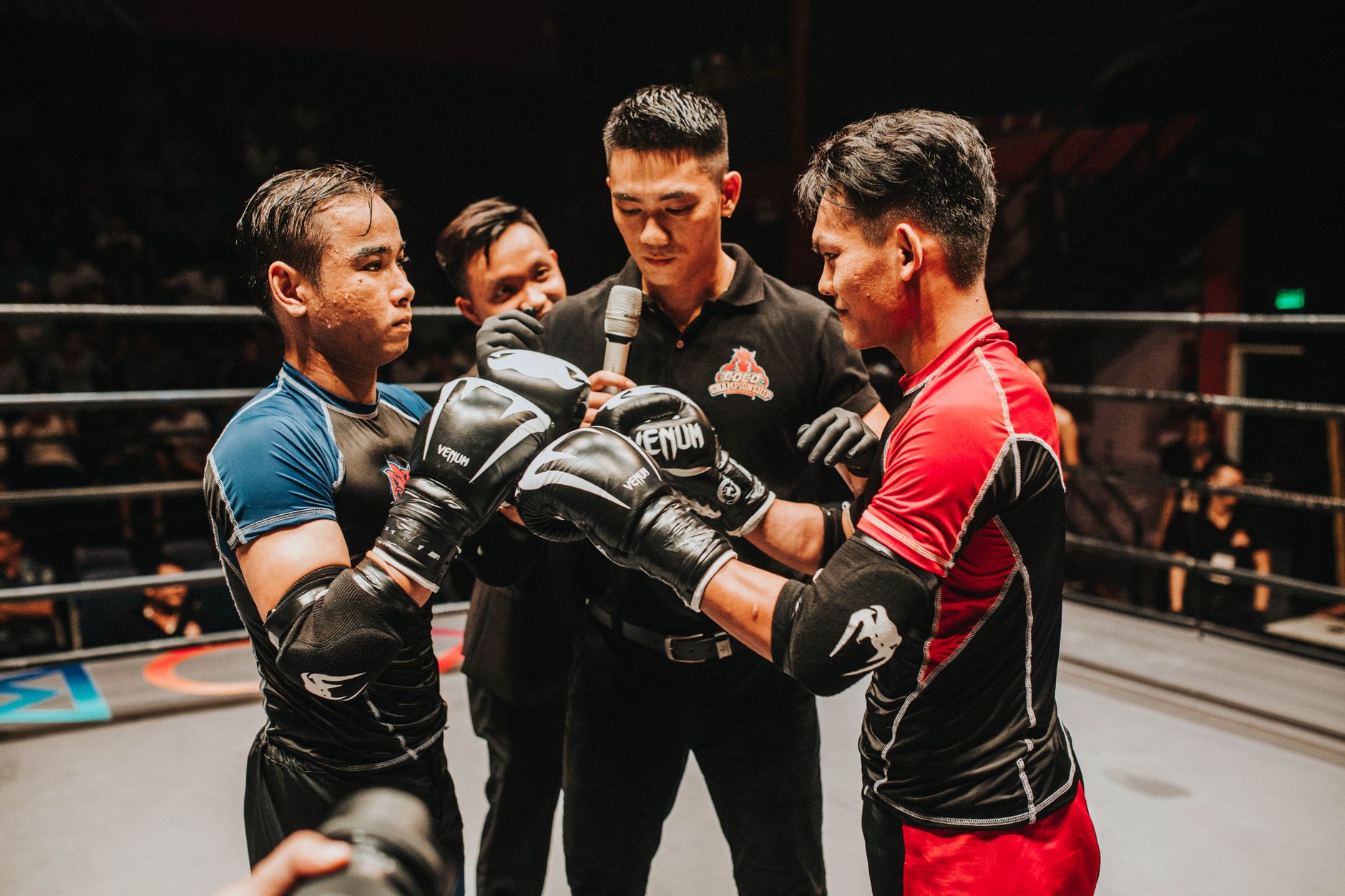 Two boxers and a referee engage in an intense pre-fight moment in the boxing ring.