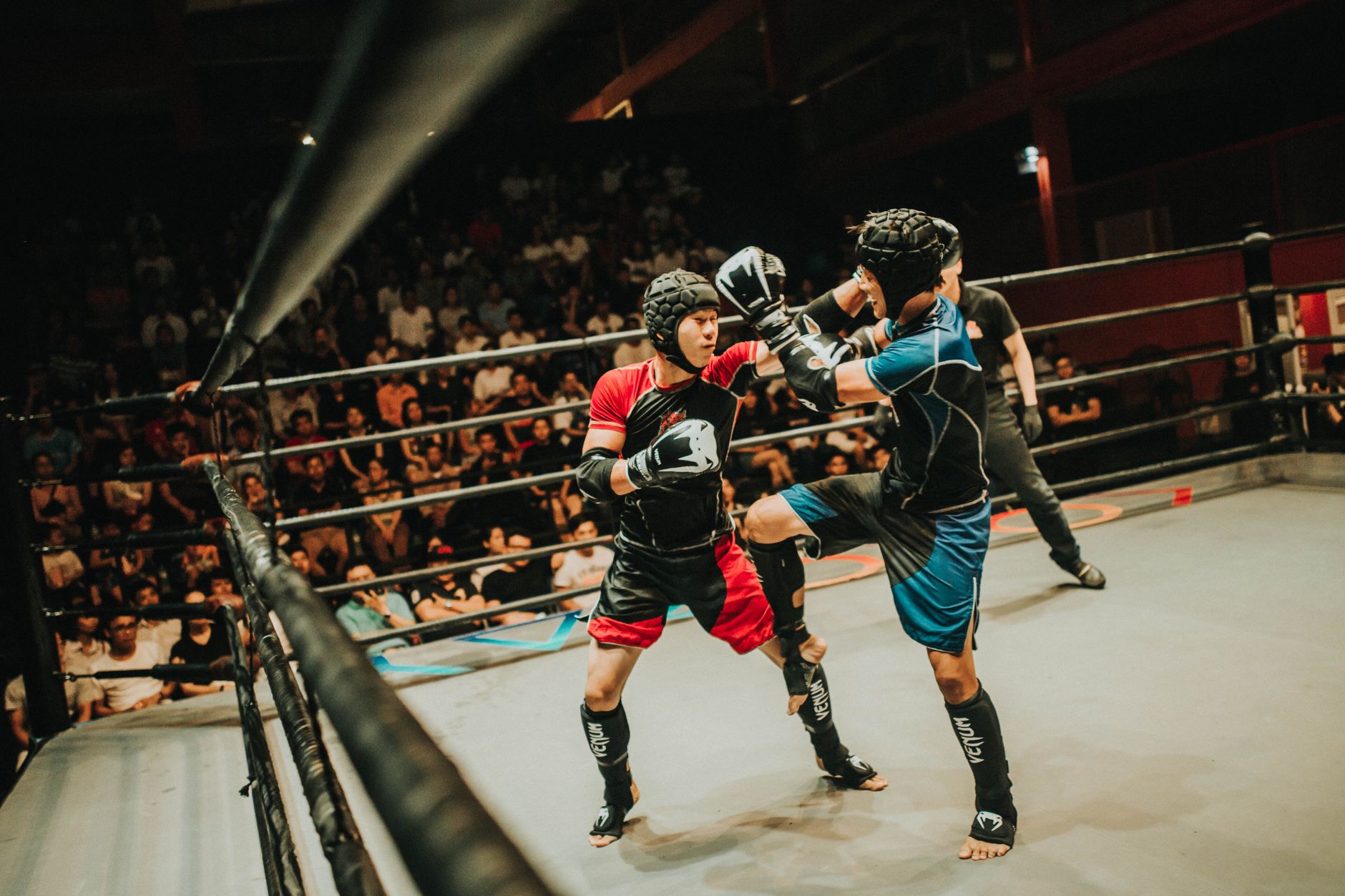 Two athletes engage in a dynamic martial arts fight in a crowded arena.