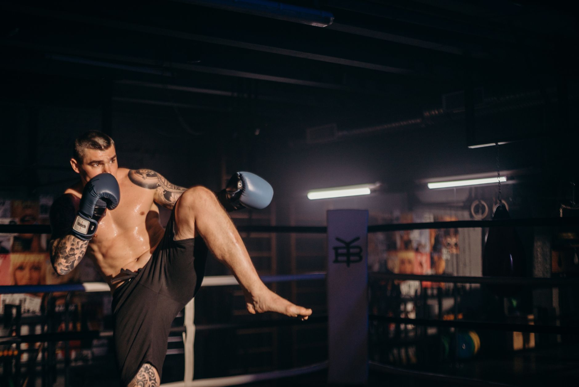 Focused kickboxer executes a high kick during an intense boxing session in the gym.