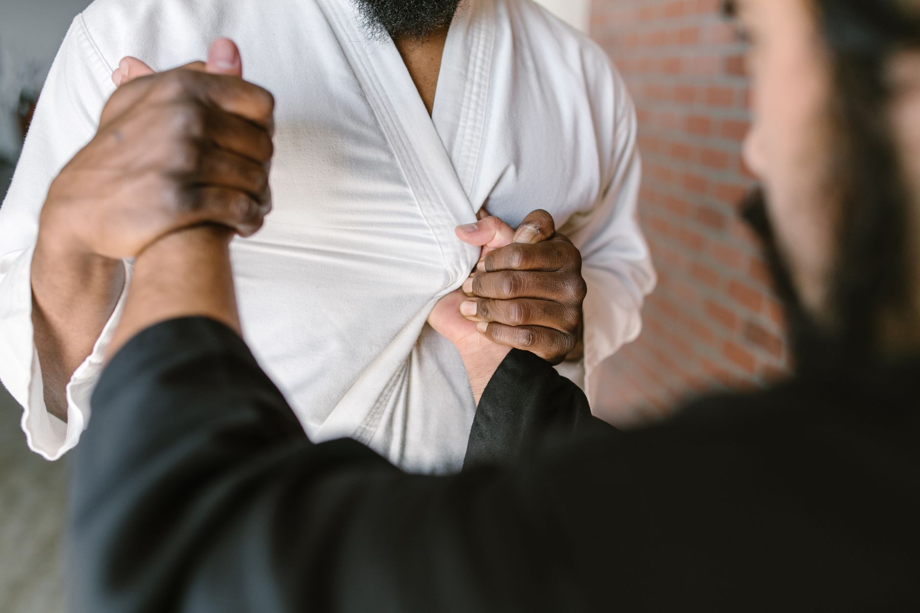 Focused view of martial artists practicing a grip technique indoors.