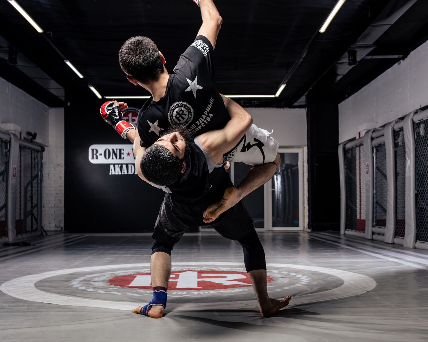 Two men engaging in dynamic martial arts grappling on a professional mat.