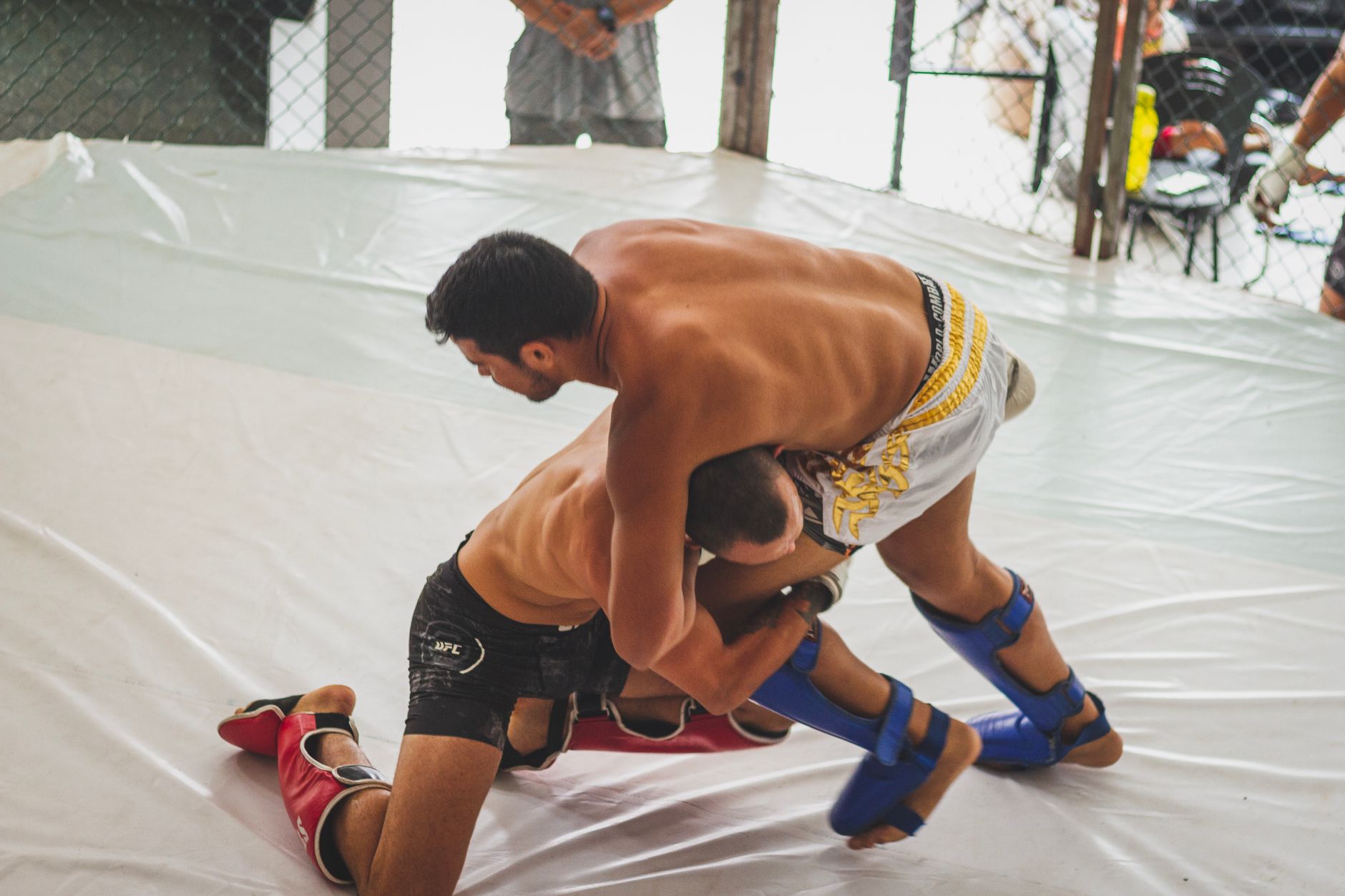 Two fighters engaged in dynamic MMA grappling inside the ring during a sparring match.