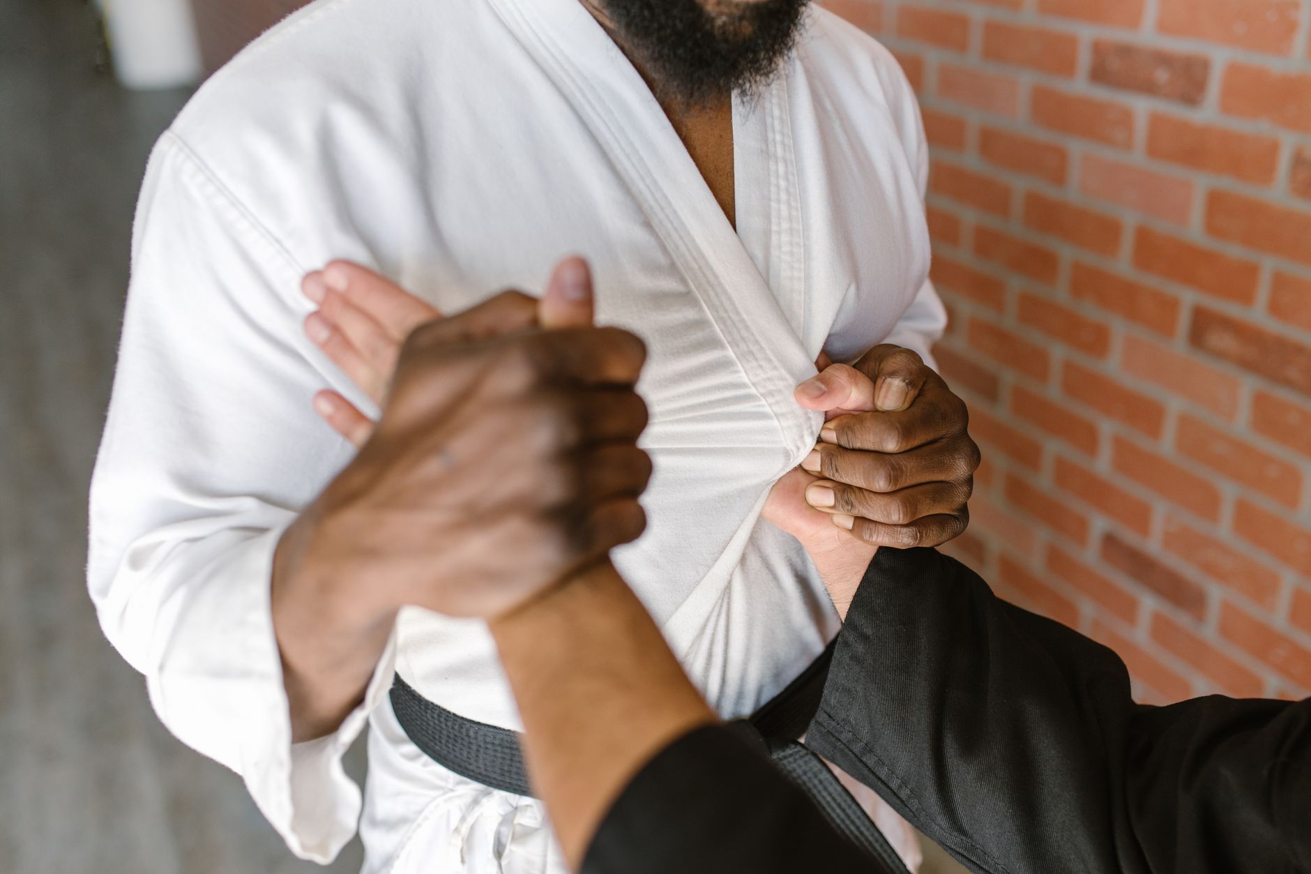 Close-up of two martial artists practicing grip techniques in a dojo.