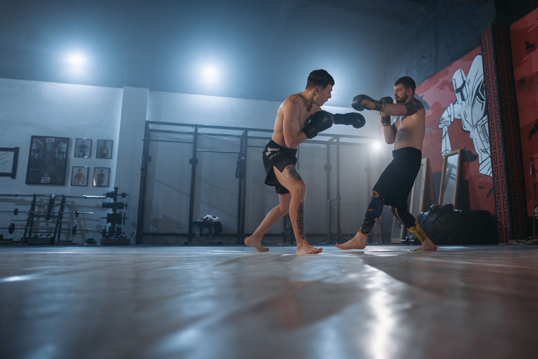 Two fighters engage in MMA sparring in a well-equipped gym setting.