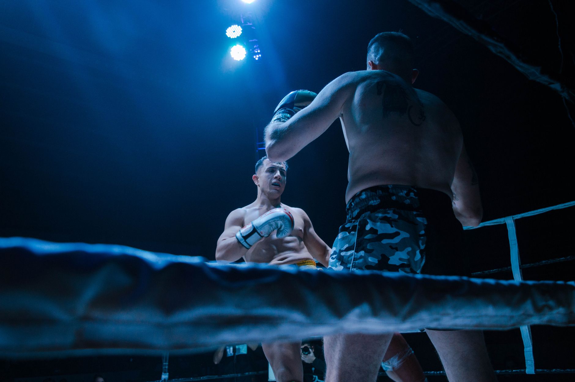 Two athletes engaging in a dynamic boxing match under bright ring lights.