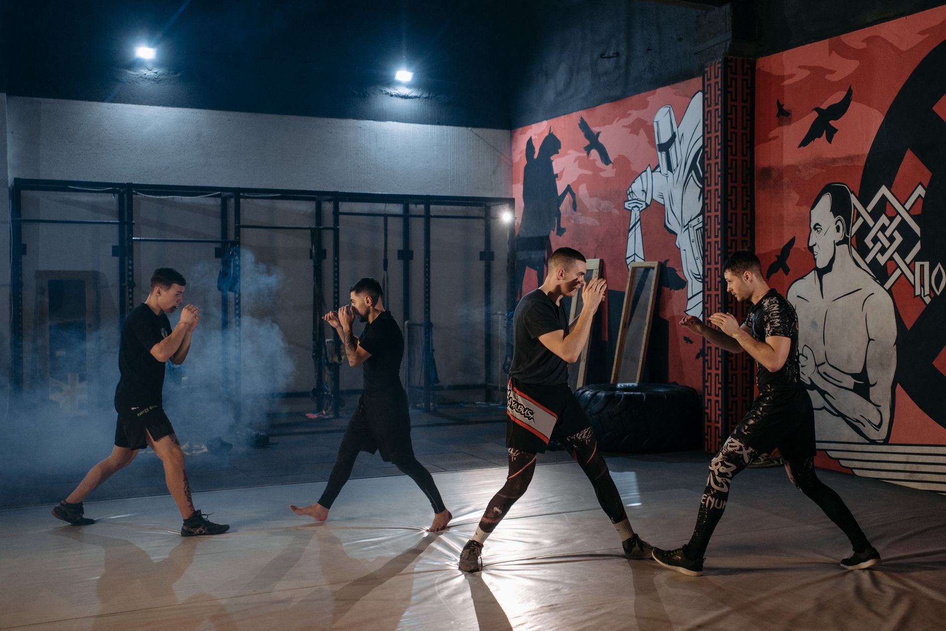Group of men engaging in MMA sparring and training in a gym setting.