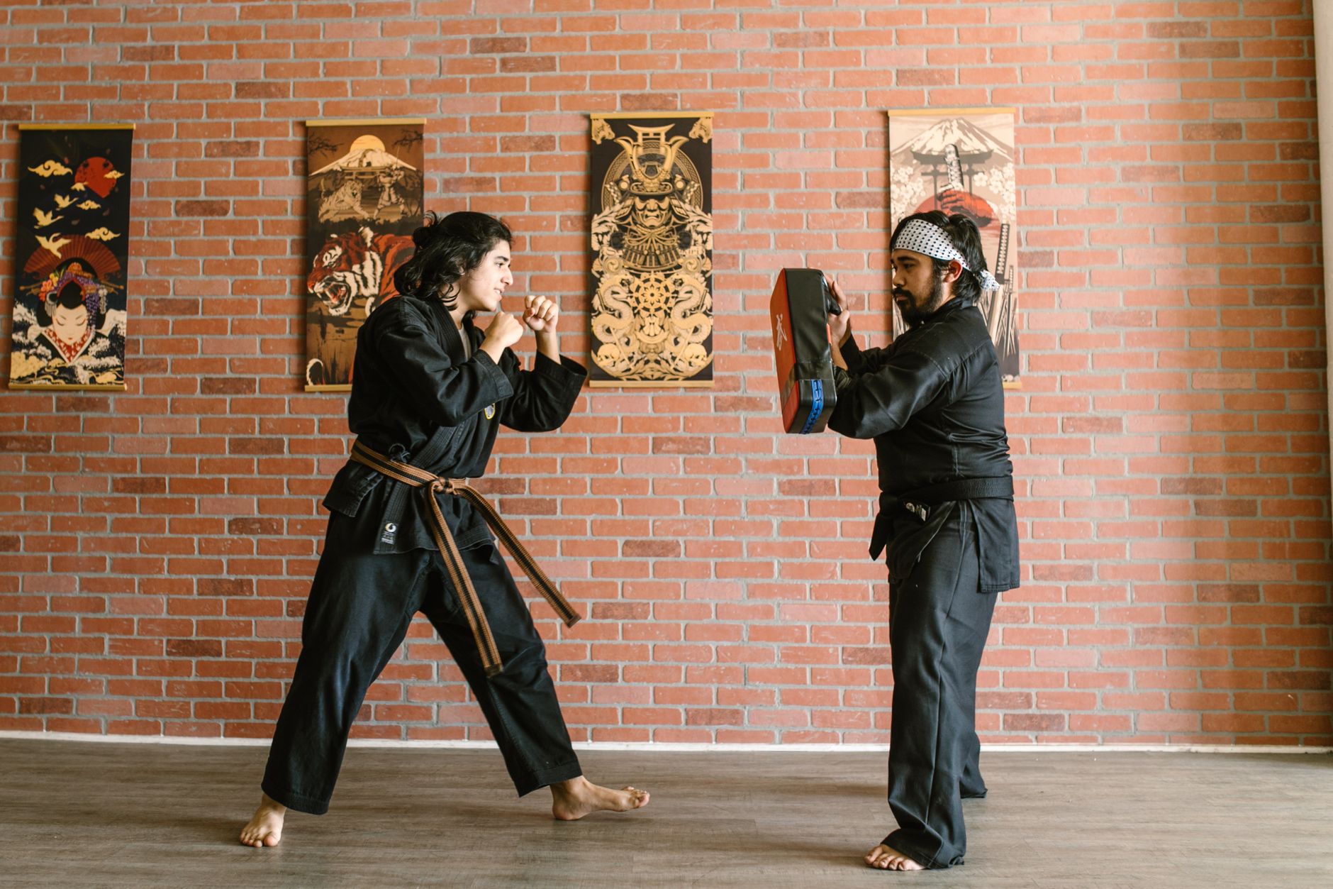Two martial artists engage in training within a dojo setting, focusing on technique.