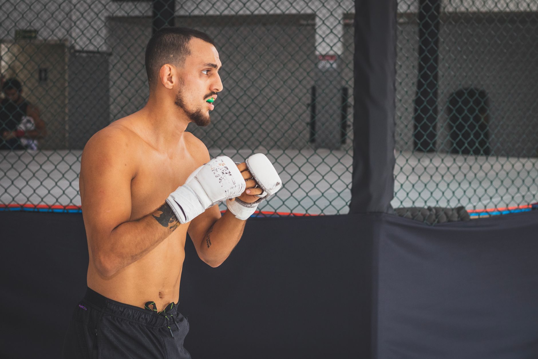 A male boxer in a gym wearing gloves, training intensely.
