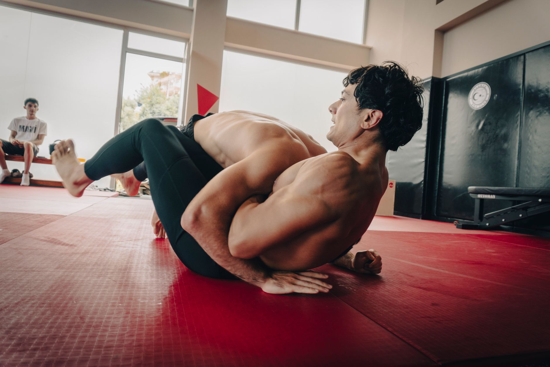 Two athletes engaged in a grappling match in an indoor gym, showcasing strength and technique.