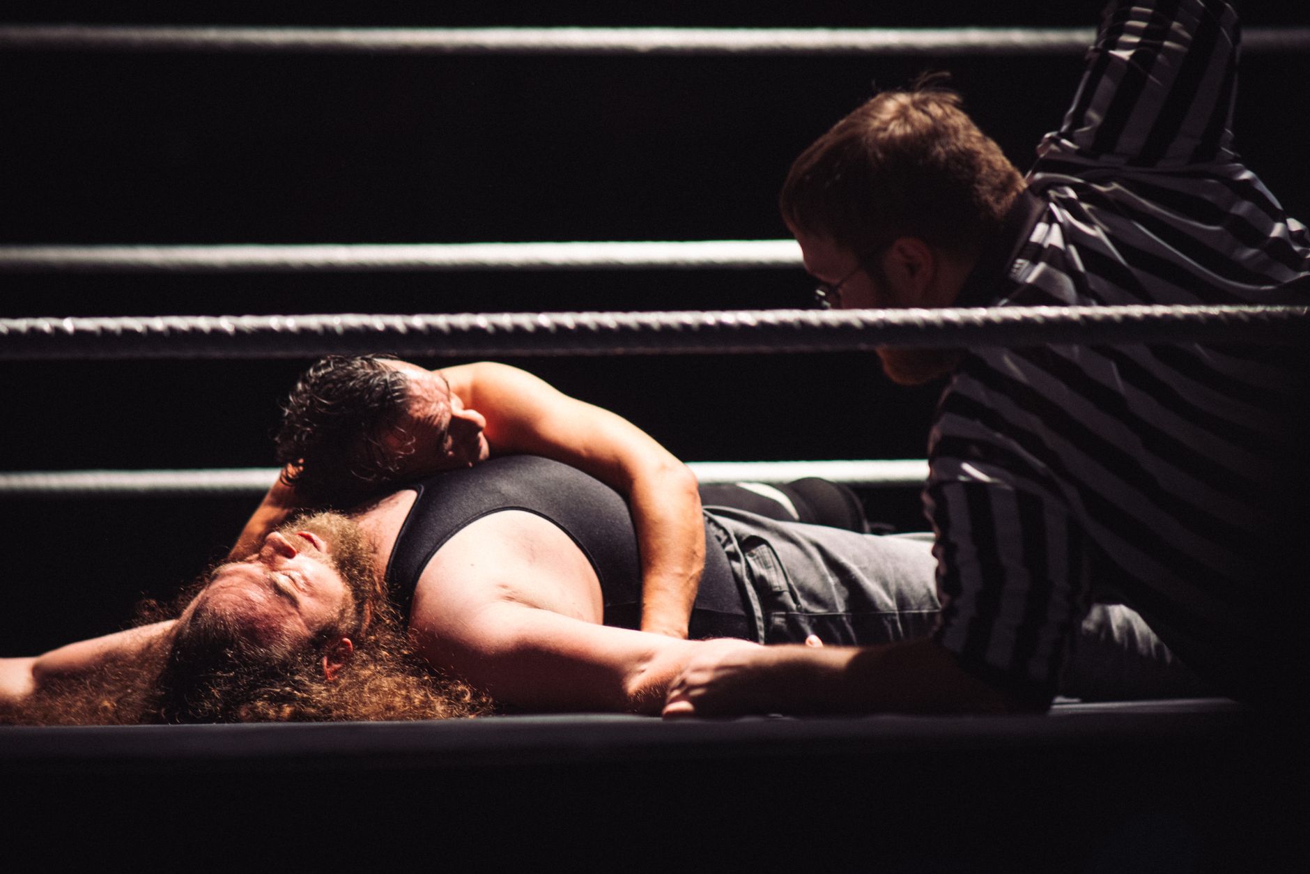 Intense wrestling match showcasing a dramatic pinfall with referee counting.