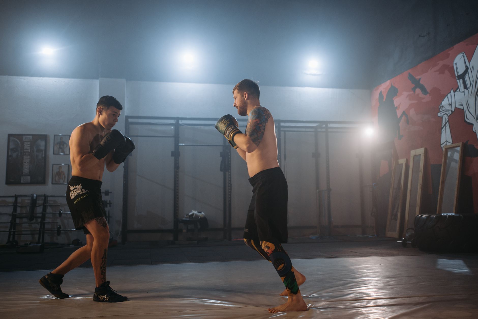 Two men sparring in a boxing gym, showcasing focus and determination under dramatic lighting.
