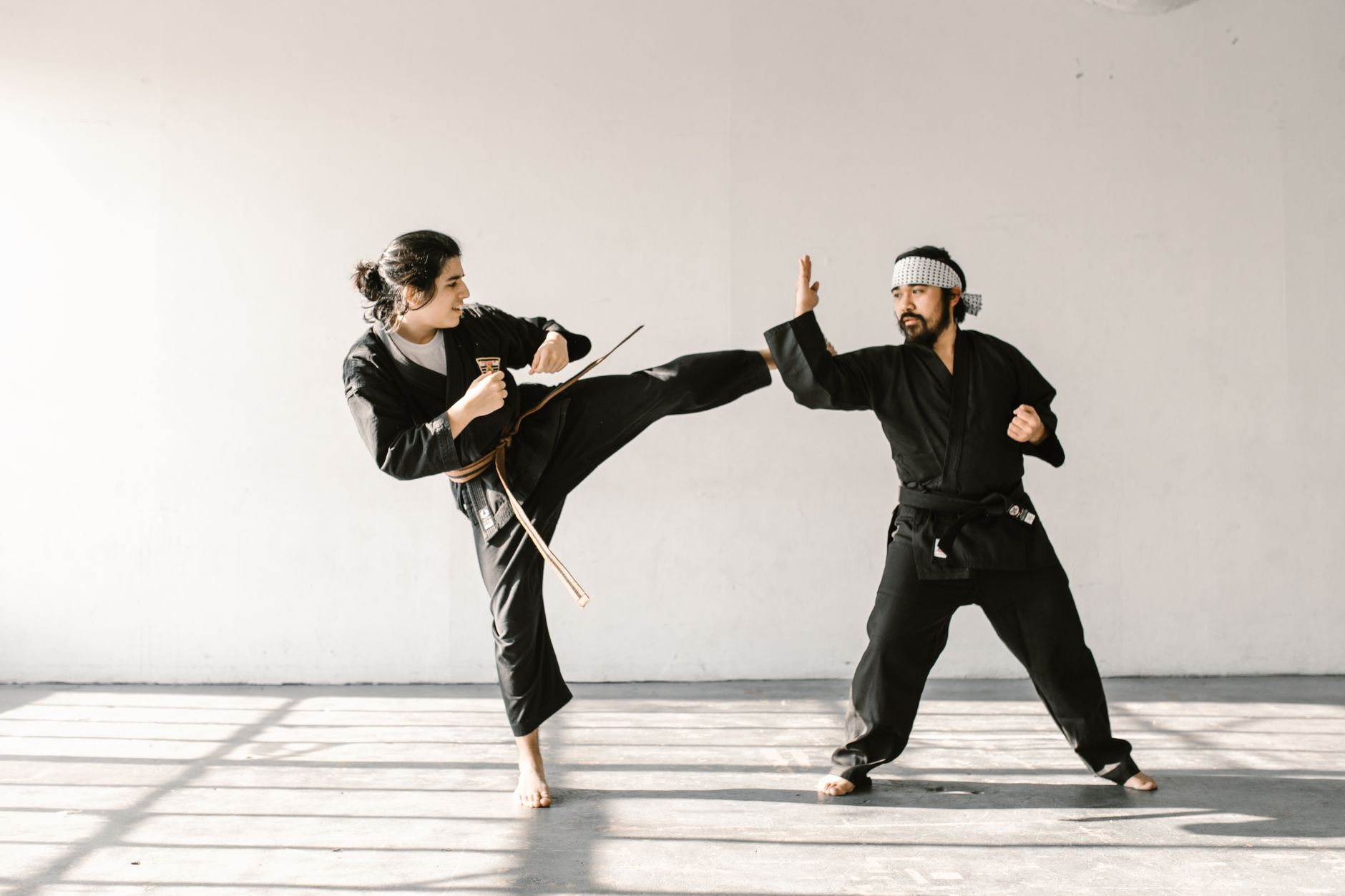 Martial artists practicing dynamic techniques in a well-lit dojo.