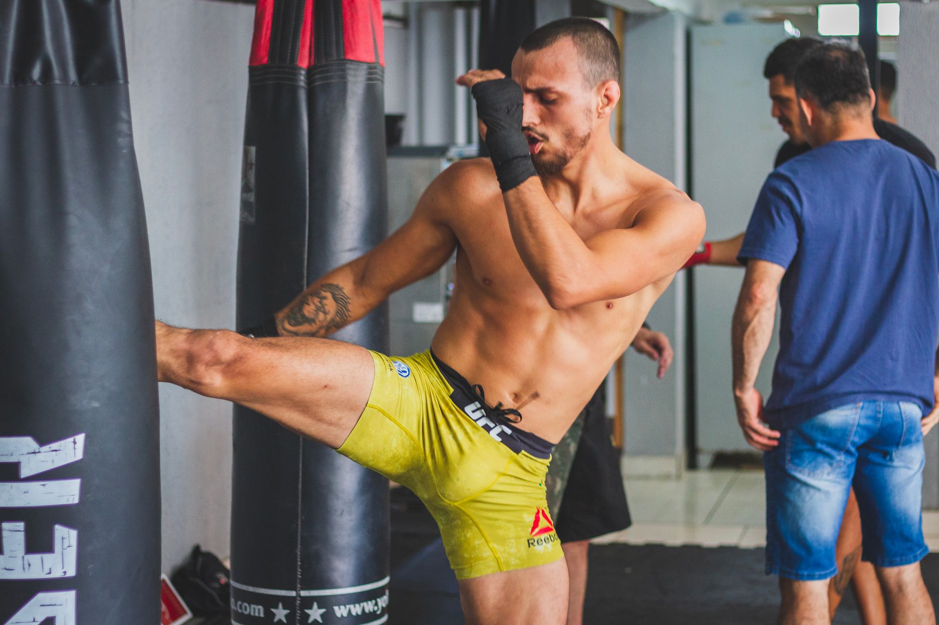 Strong male martial artist executing a powerful high kick in a gym setting.