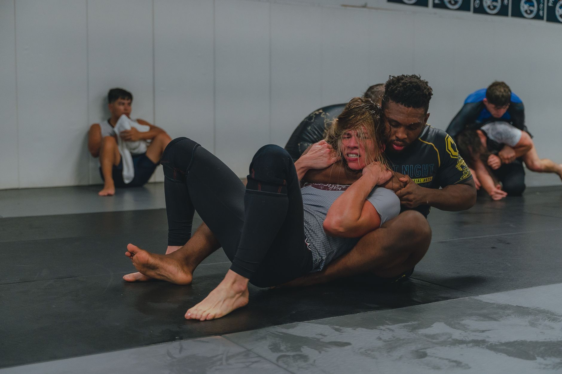 Athletes engaged in grappling training at a gym, showcasing intense focus and technique.