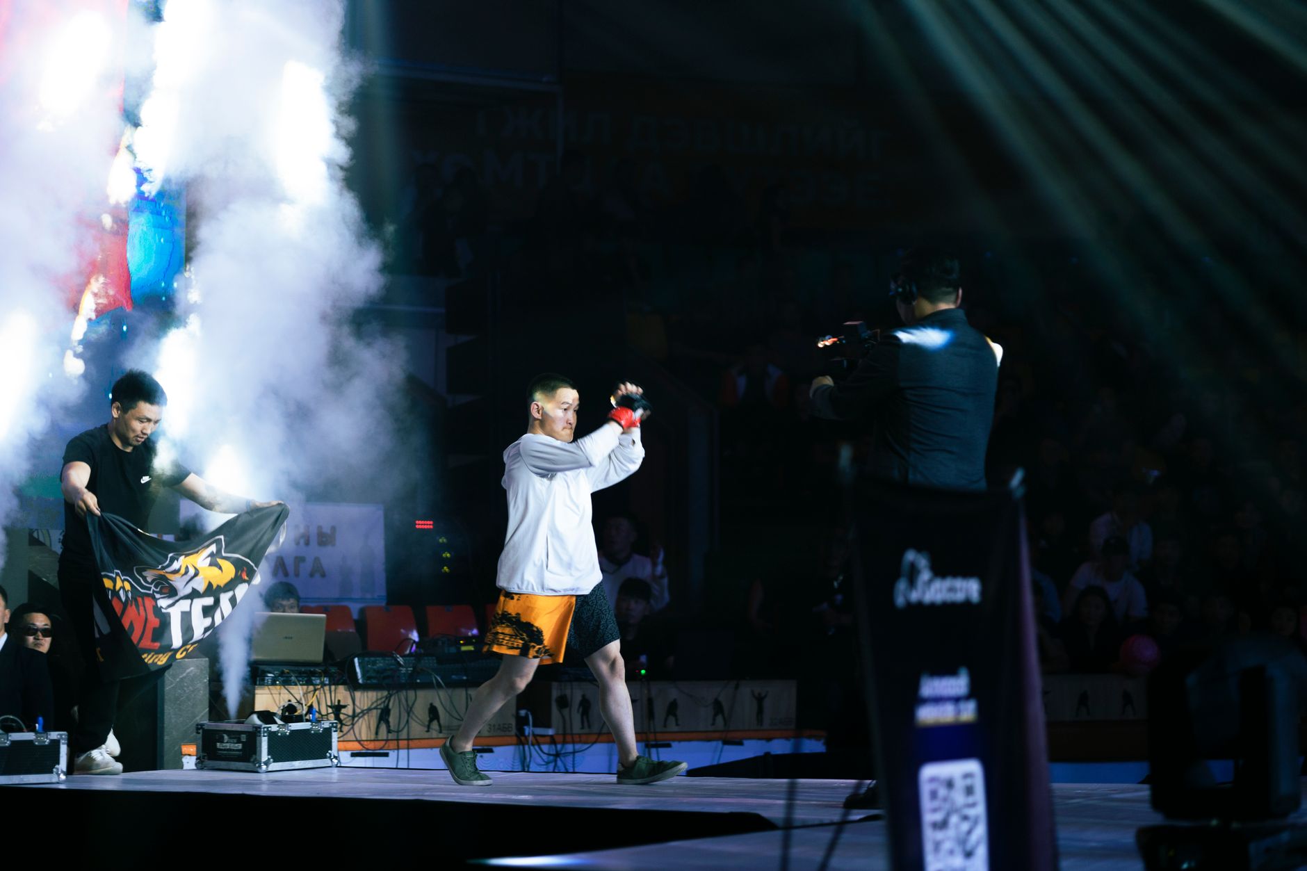Exciting entrance of an MMA fighter amidst smoke and lights in the arena.