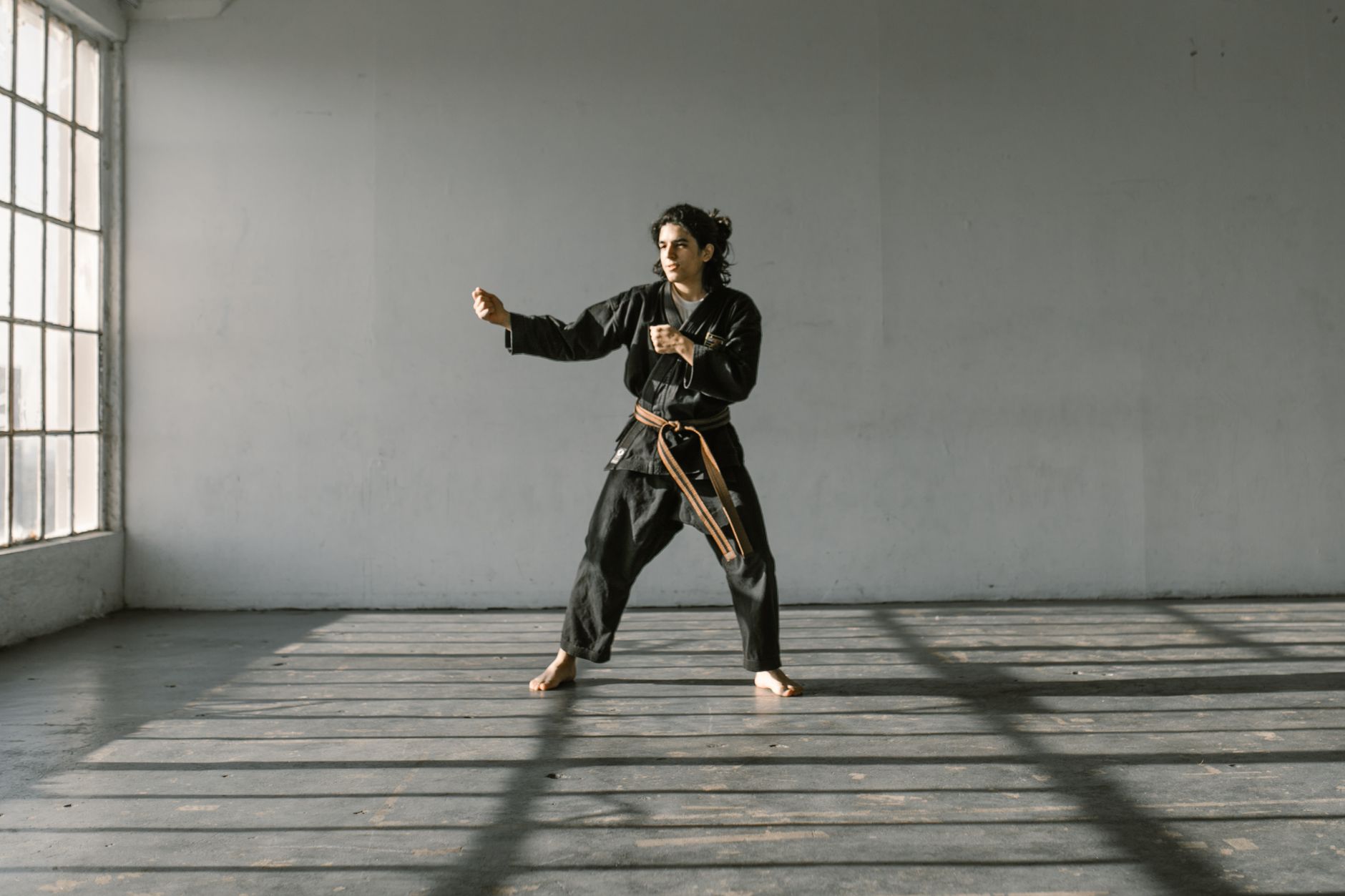 Martial artist performs a kata in a well-lit dojo, emphasizing strength and focus.