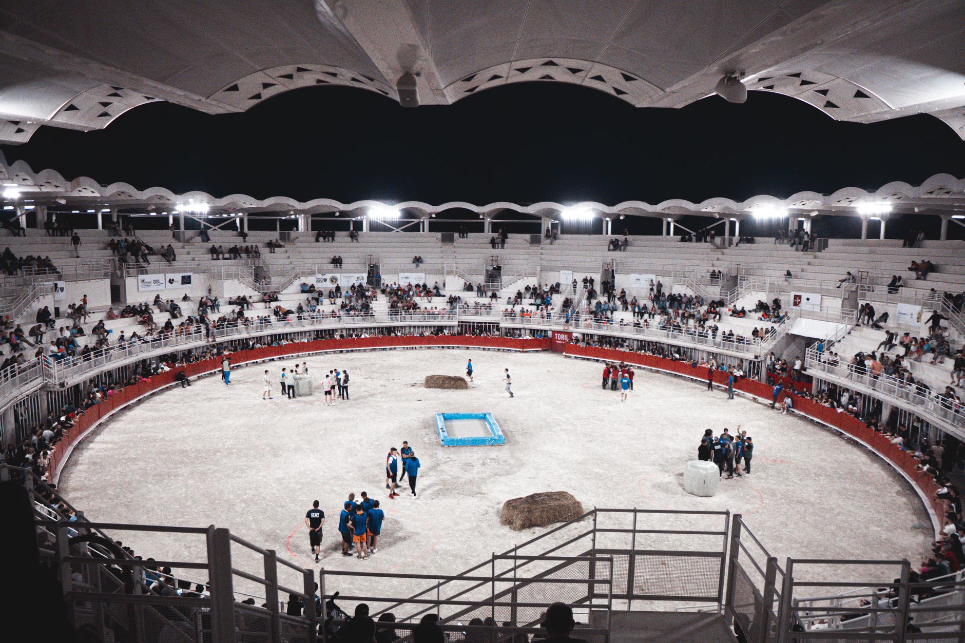 A lively scene at an indoor sports arena filled with spectators and participants at night.