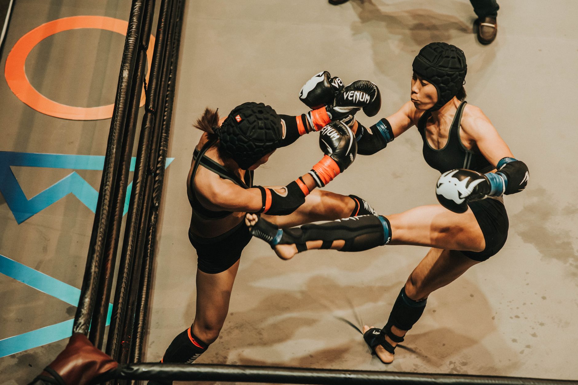 Two female athletes engaged in intense martial arts sparring session wearing protective gear.