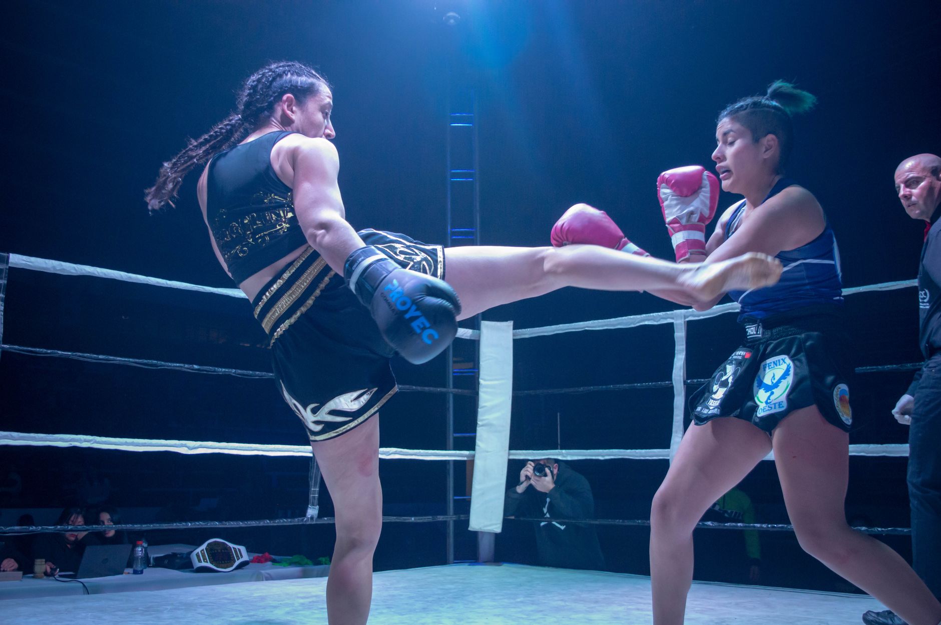 Two female kickboxers exchange powerful blows in an intense ring battle.