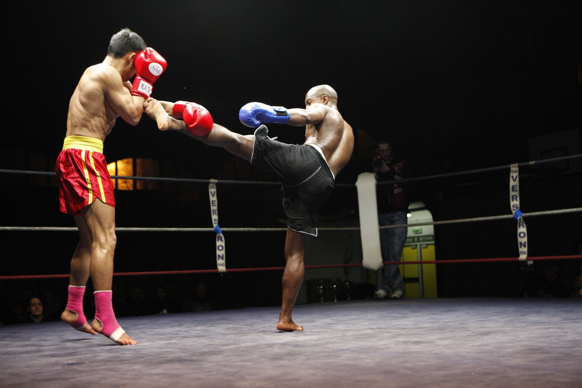 Dramatic moment of a kickboxing match with fighters in mid-action wearing gloves.