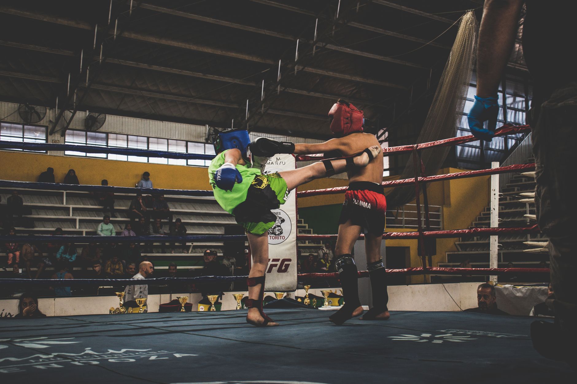 Exciting indoor kickboxing match with athletes exchanging kicks in a vibrant sports arena.
