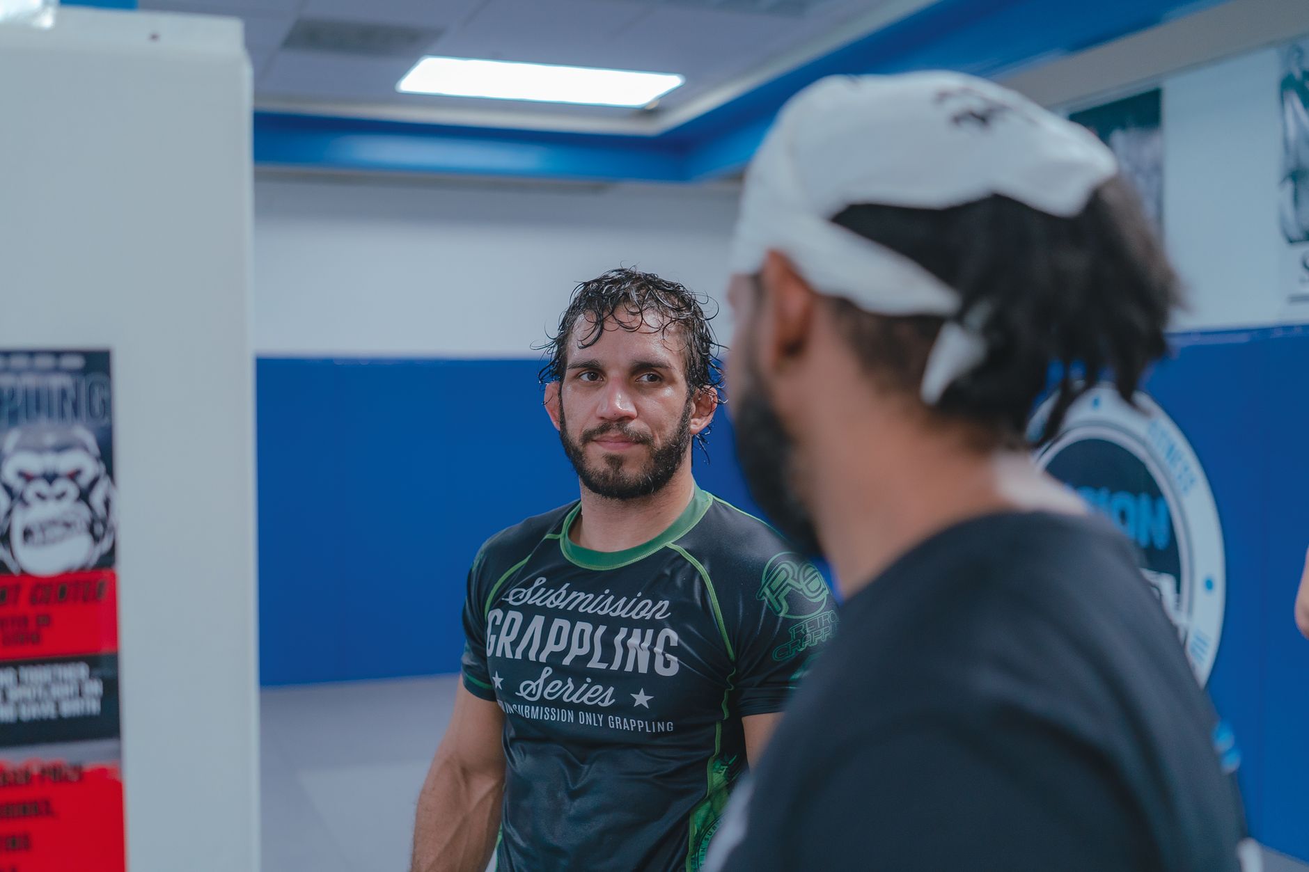 Athletes engaging in martial arts training session in an indoor gym.